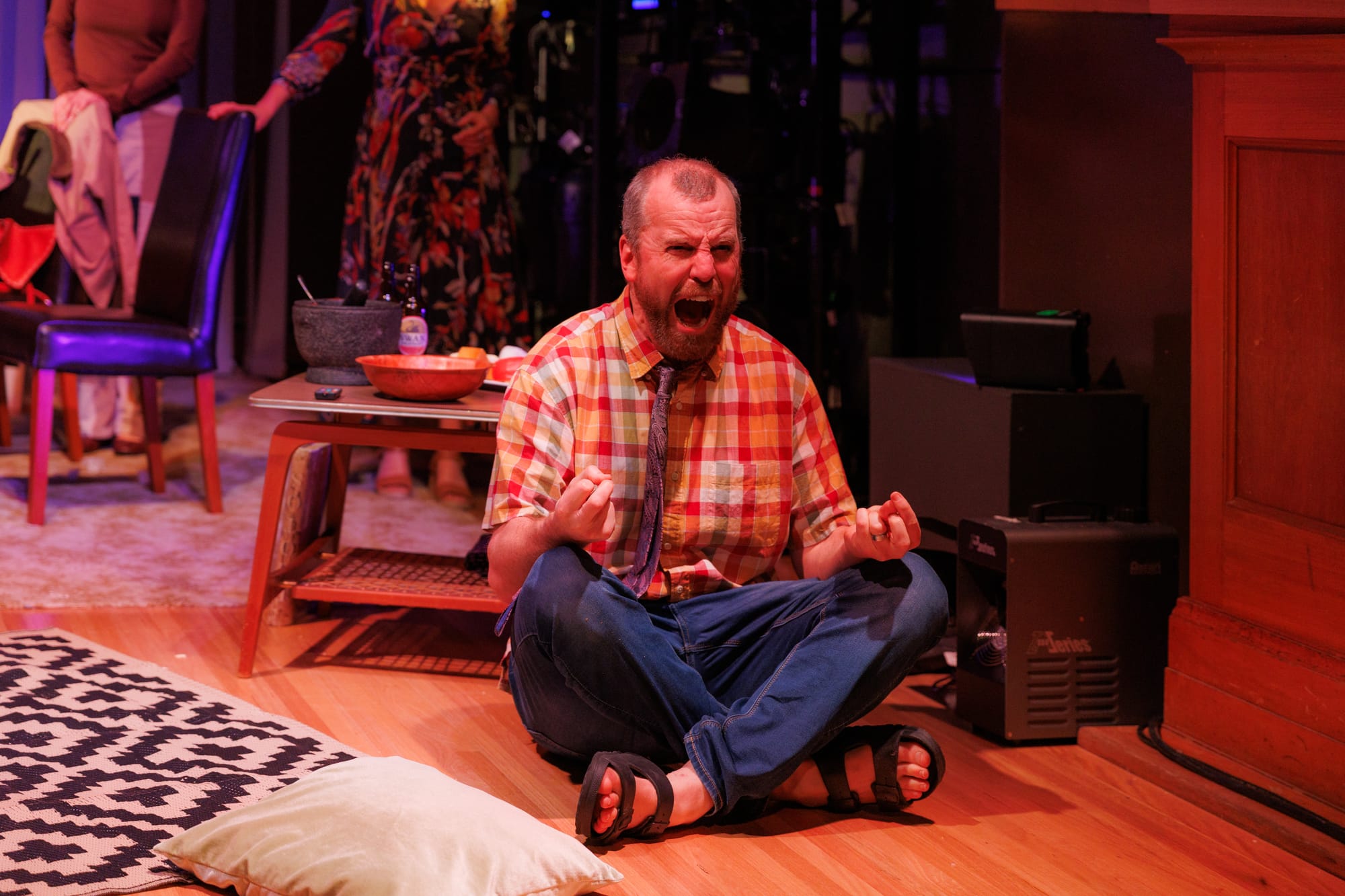 Lee sits cross-legged on the floor, shouting with his fists clenched during a heightened moment in Cut Chilli.