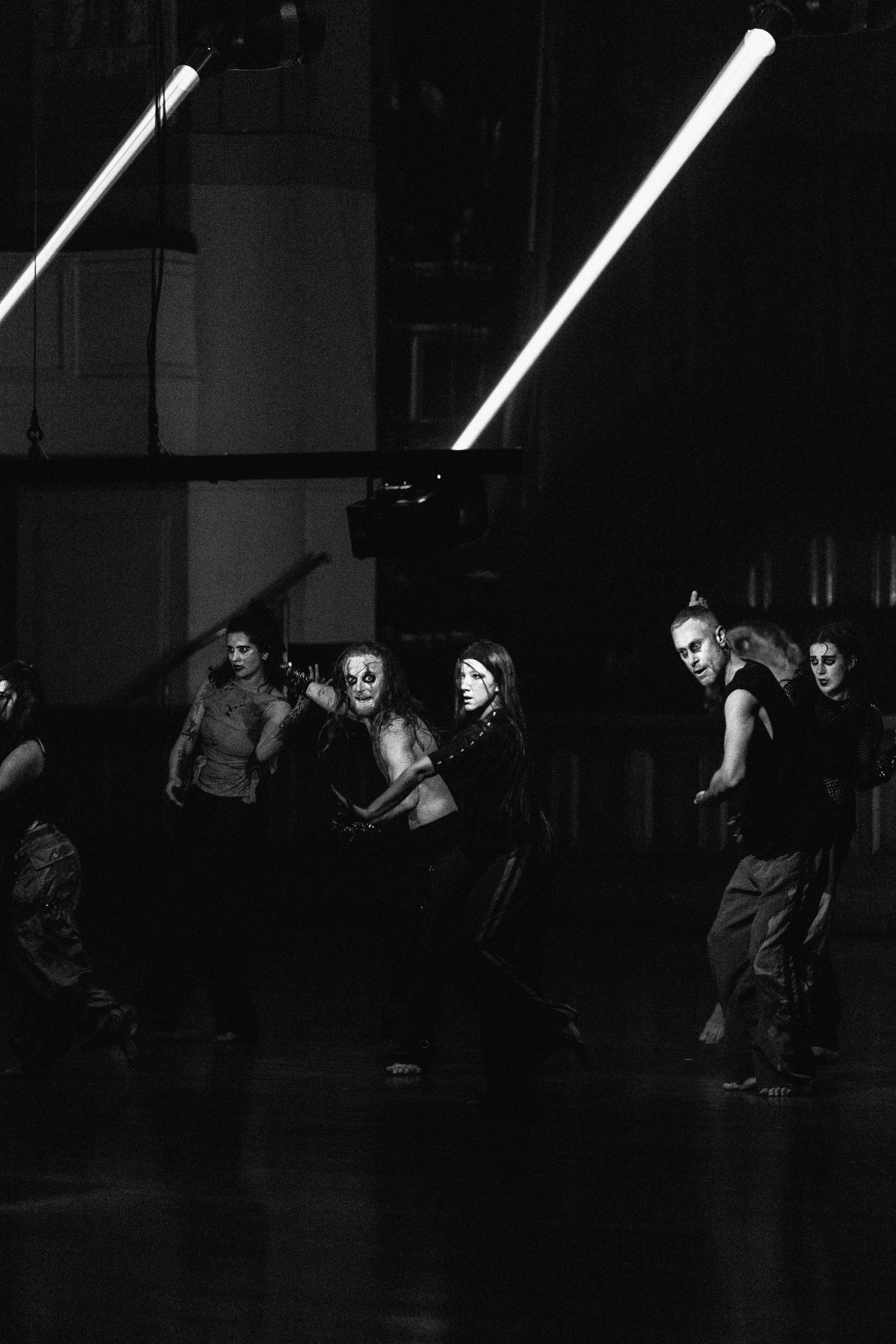 Six dancers with pale theatrical makeup cluster together in the darkened Melbourne Town Hall, their bodies caught mid-movement beneath bright diagonal laser beams in Chunky Move’s Time Remaining.