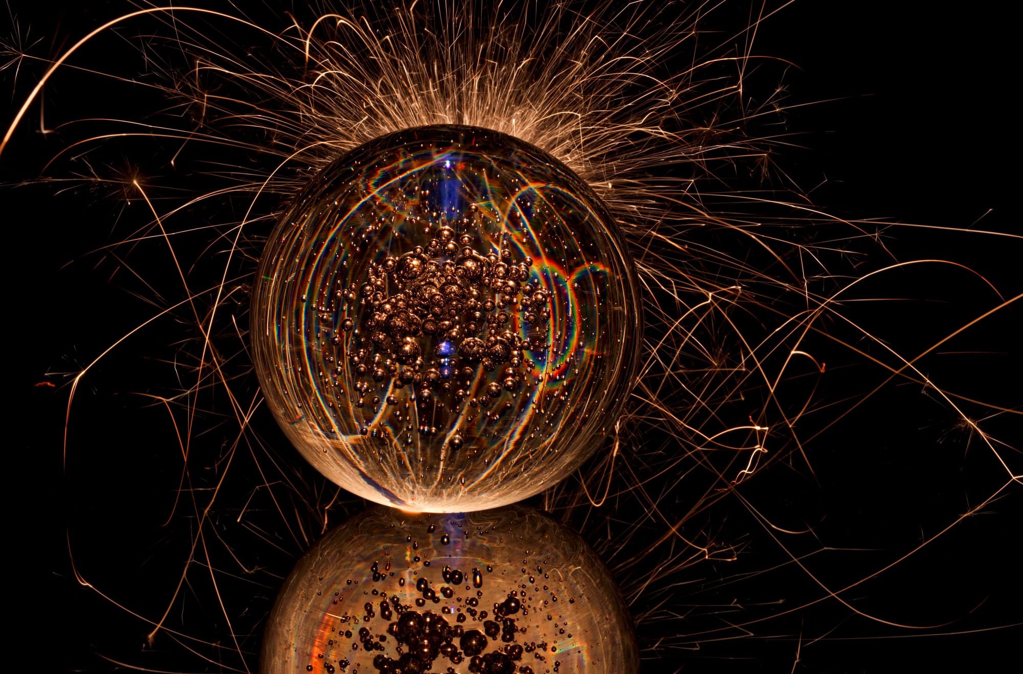 An illuminated glass sphere surrounded by looping trails of orange light against a dark background.