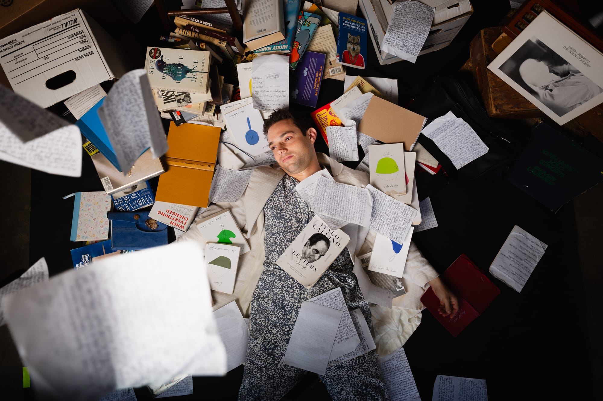Gregory Nussen lies on the floor surrounded by scattered books, papers and notebooks.
