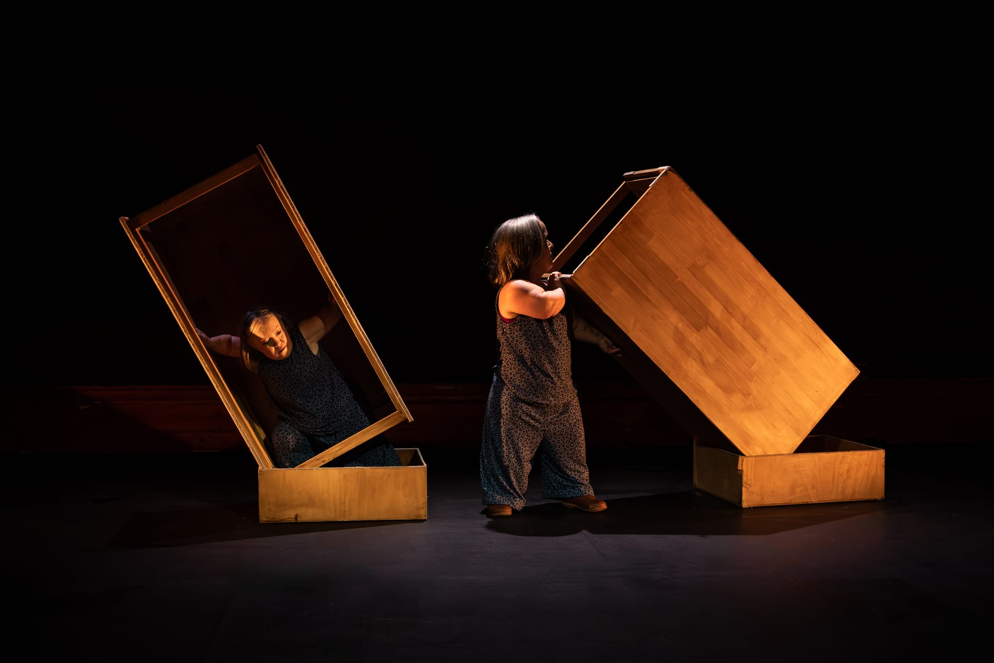 Hawkins and Prowd emerge from plywood boxes, tipping and pulling the structures apart on a darkened stage.