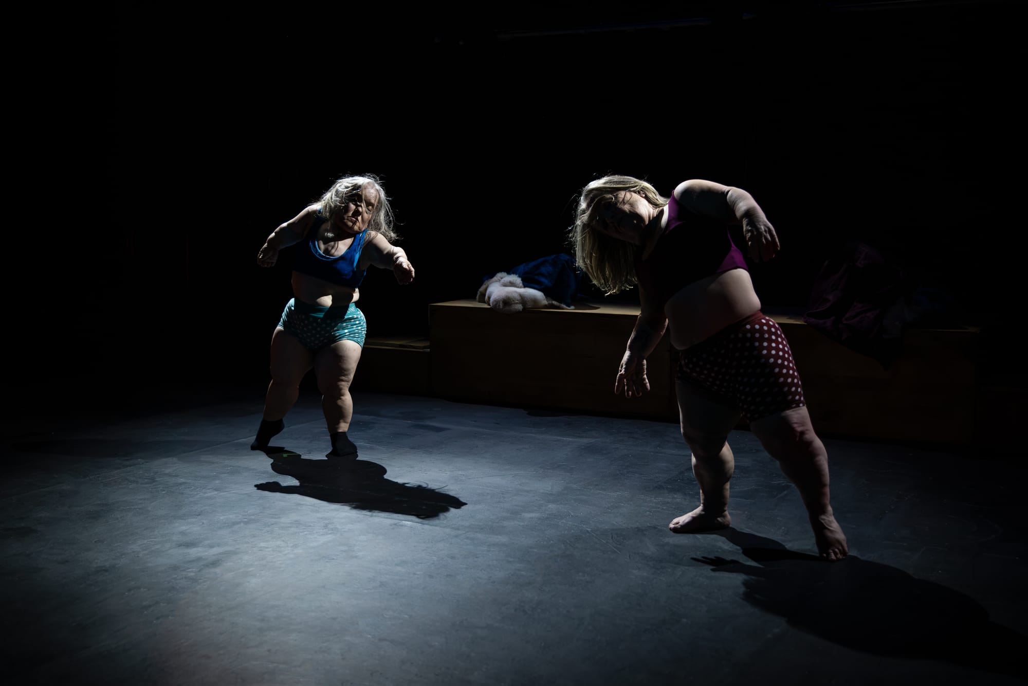 Hawkins and Prowd lean and twist through a dance sequence in pools of low light, their shadows stretching across the stage.