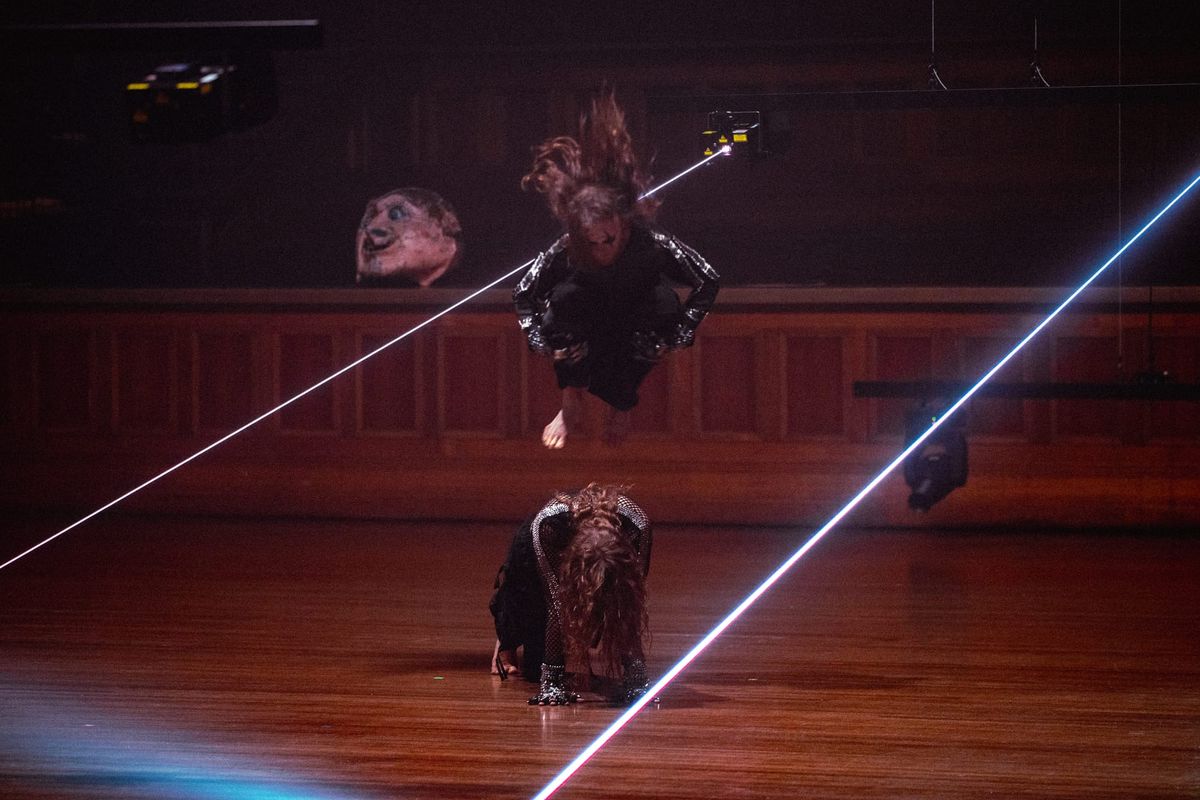 One dancer leaps above another crouched on the timber floor as blue-white laser beams slice across Melbourne Town Hall in Chunky Move’s Time Remaining.