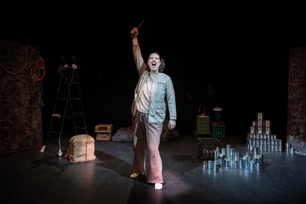 Jamila Main as Cam stands in the burrow, holding a knife aloft.