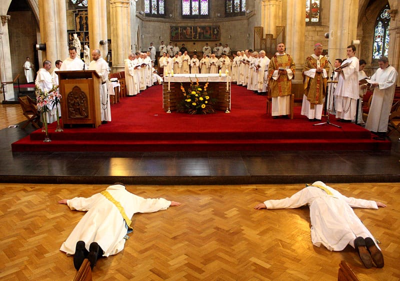 two new priests lie in prostration—face down, arms spread out, feet together