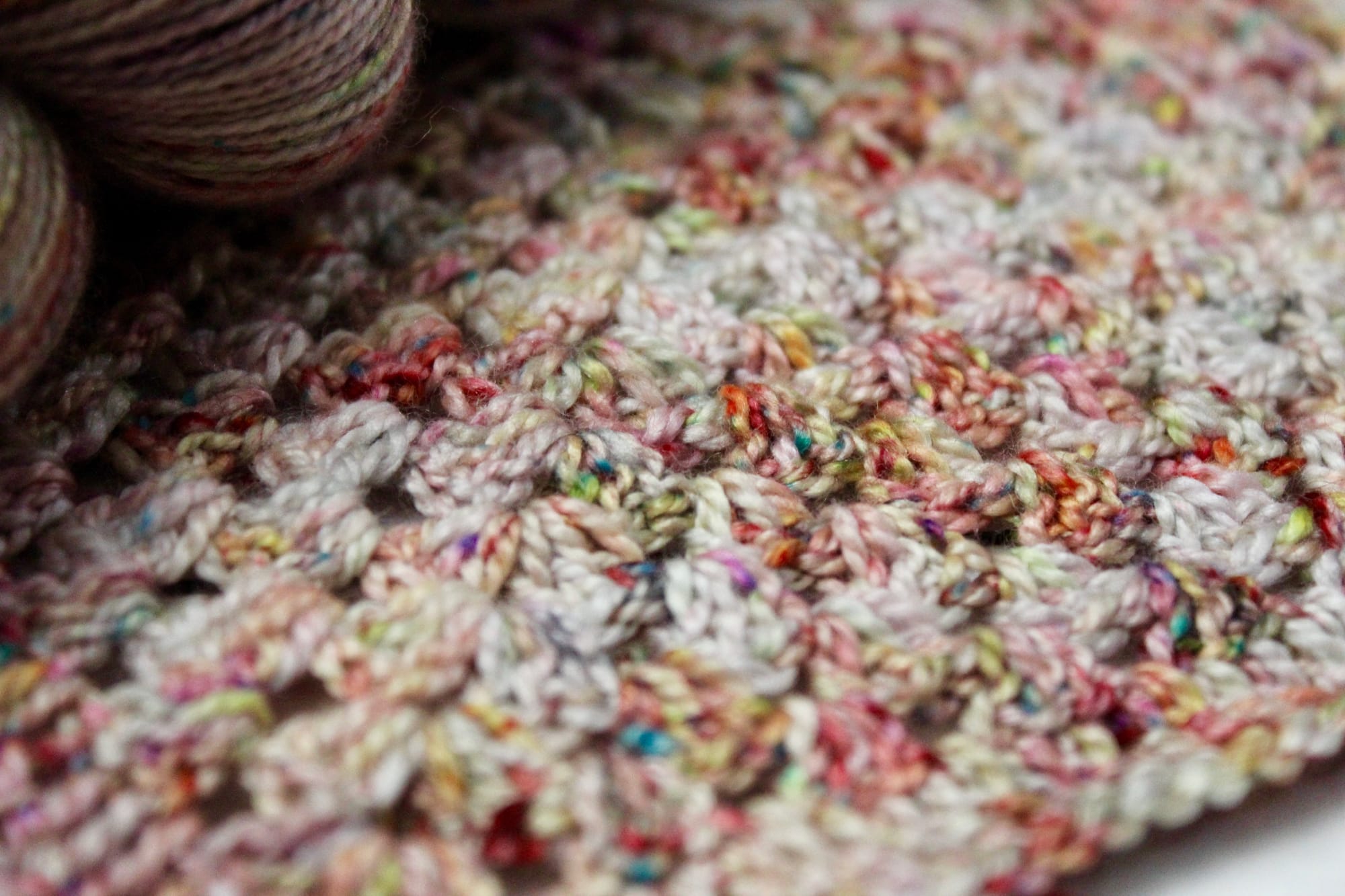 Close-up of a multicolored crochet pattern with visible yarn skeins.