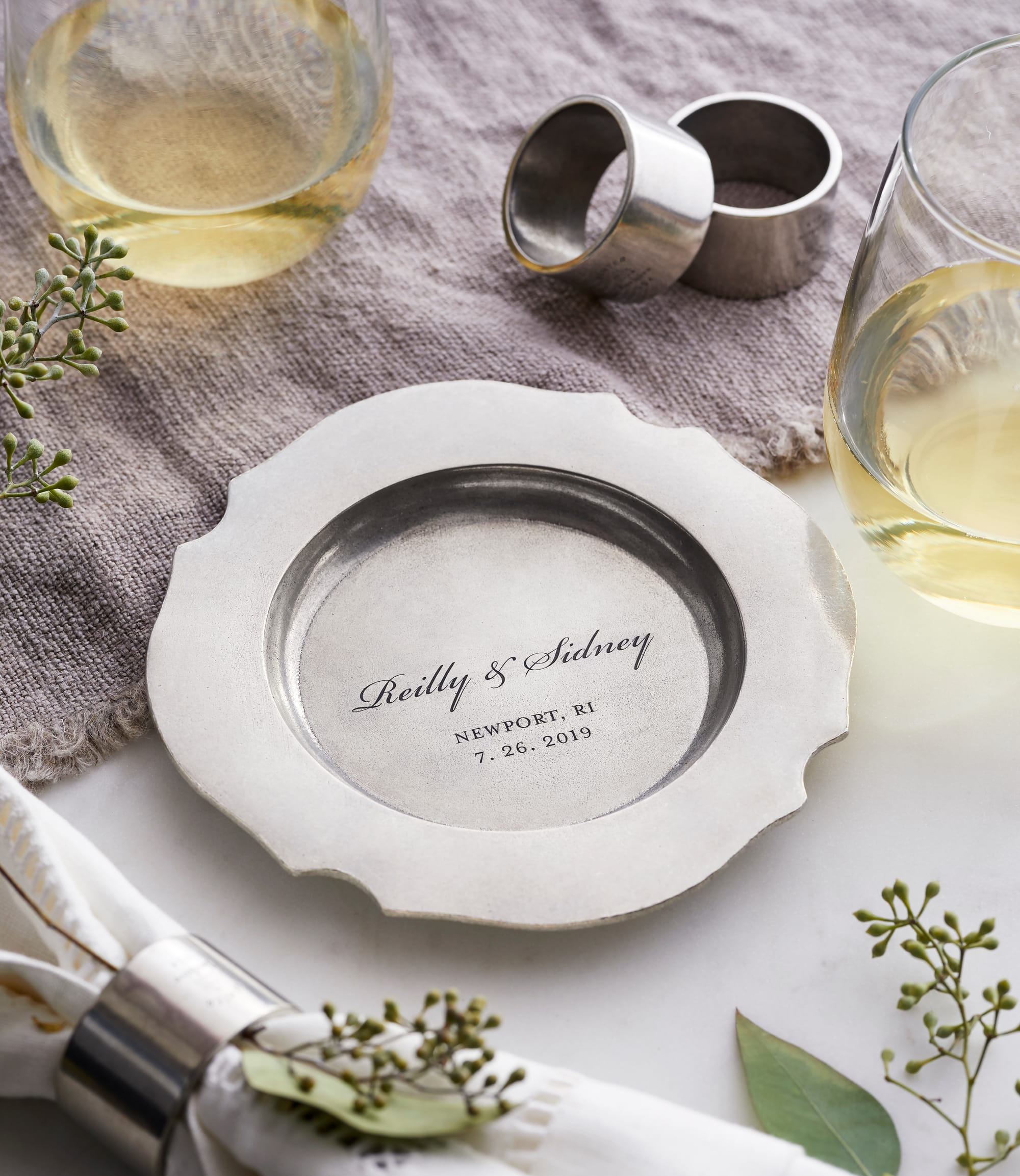 Silver plate engraved with "Reilly & Sidney, Newport, RI, 7.26.2019" on a cloth beside wine glasses. Elegant, celebratory tone.