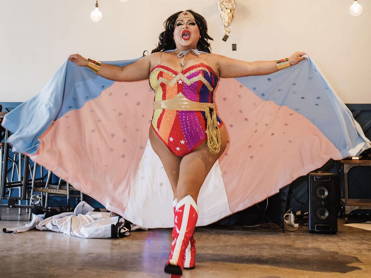 A drag performer dressed as Wonder Woman spreads her cape.