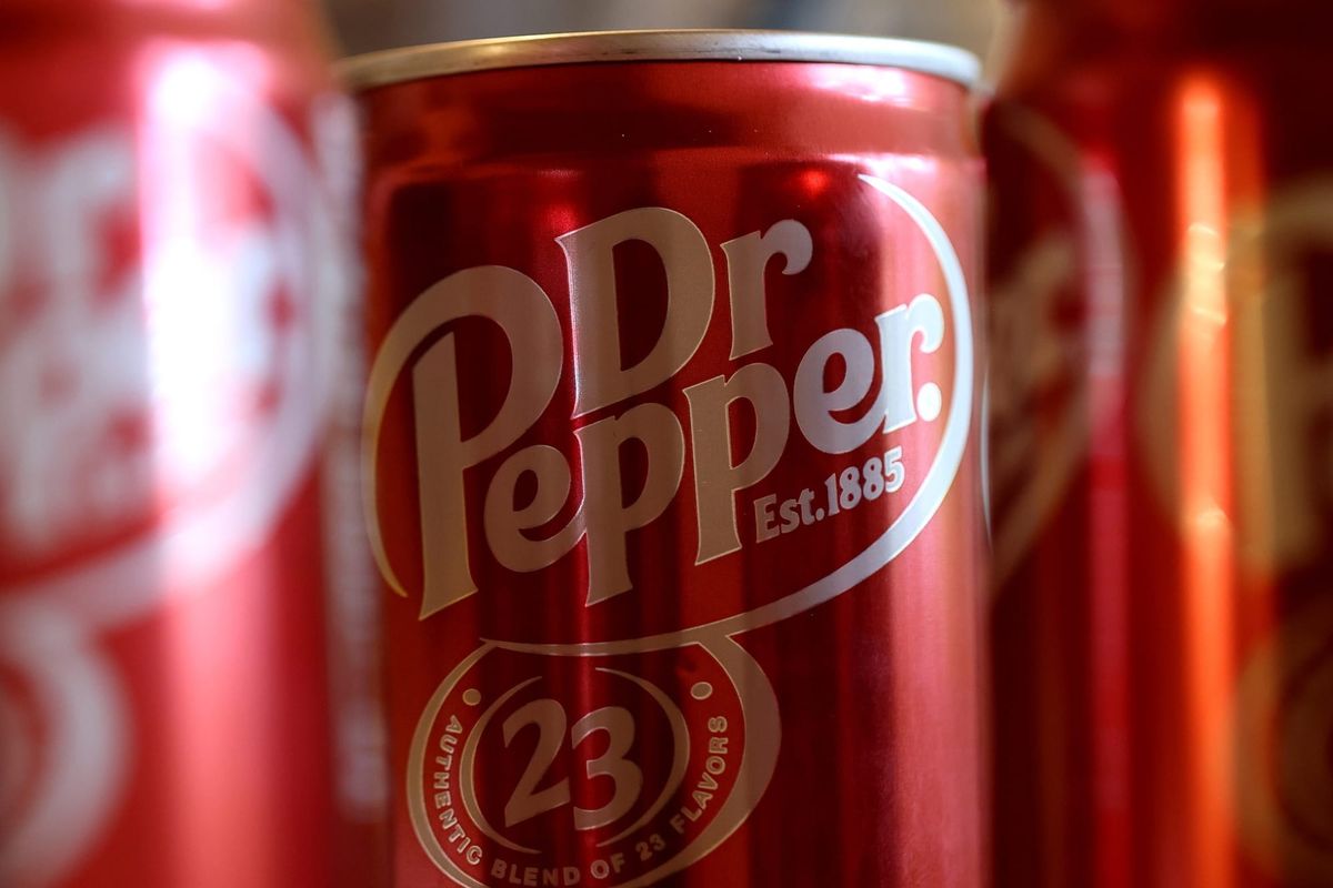 A can of Dr Pepper soda surrounded by other cans of Dr Pepper.