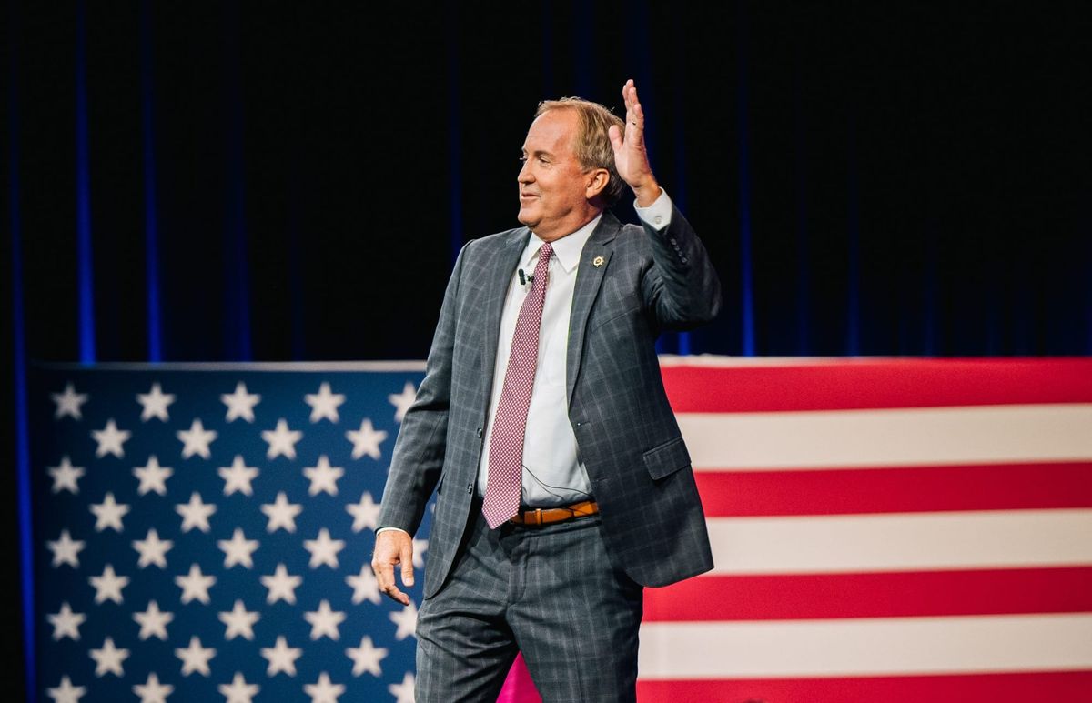 Paxton waving in front of an American flag