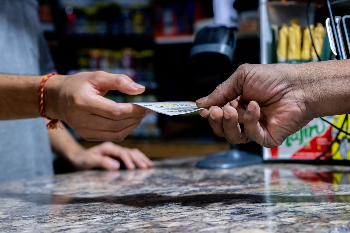 someone handing a lottery ticket across a countertop