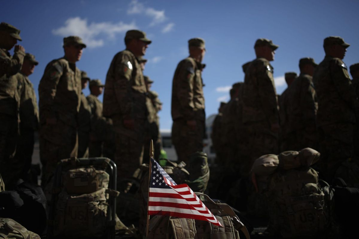 an American flag waving in front of a group of soldiers for the U.S. Army