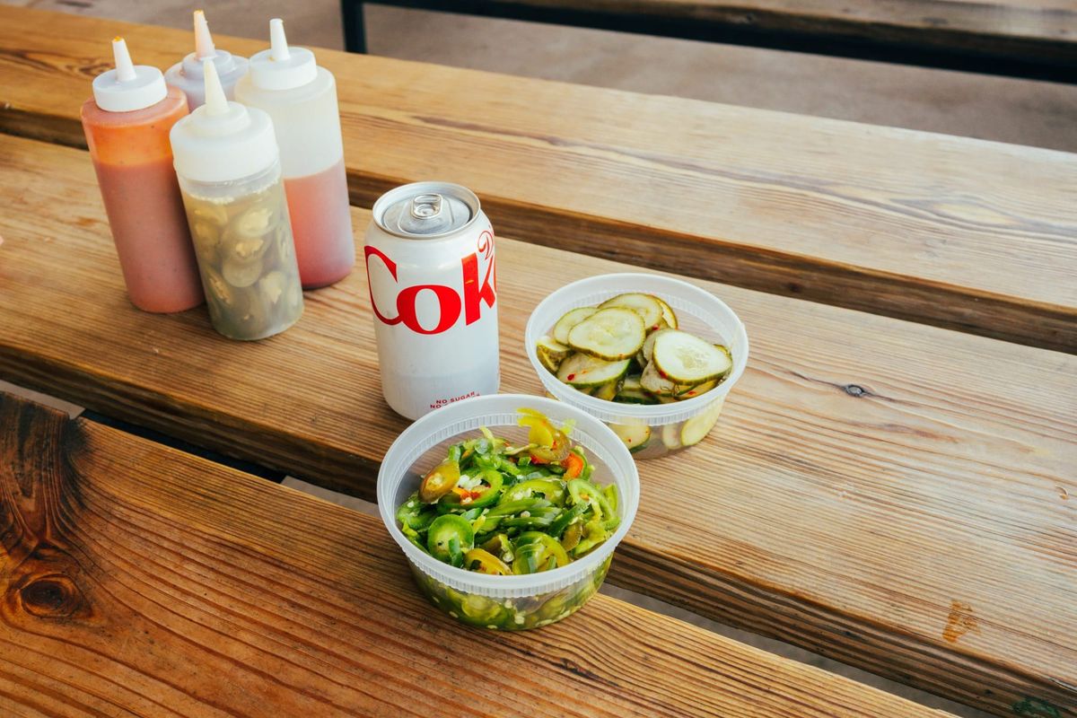 A diet coke, some sauces, pickles, and jalapenos