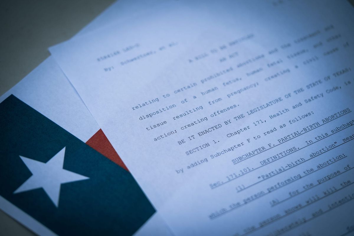 A court document, Texas’ abortion law, resting on top of a Texas flag on a desk
