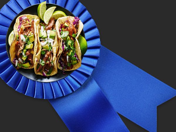 Three tacos on a blue ribbon over a black background.
