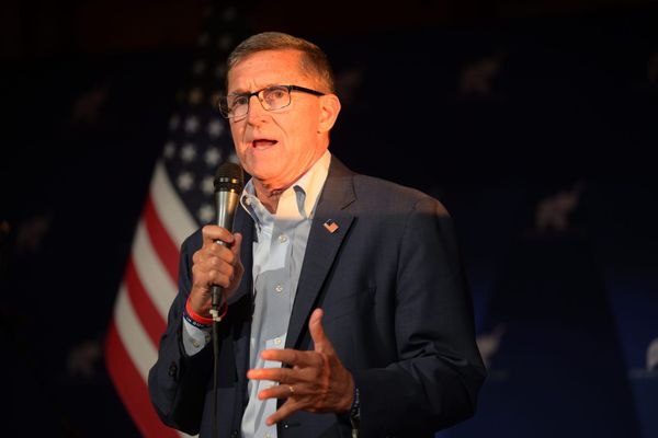 Michael Flynn holding a microphone in front of an American flag on stage