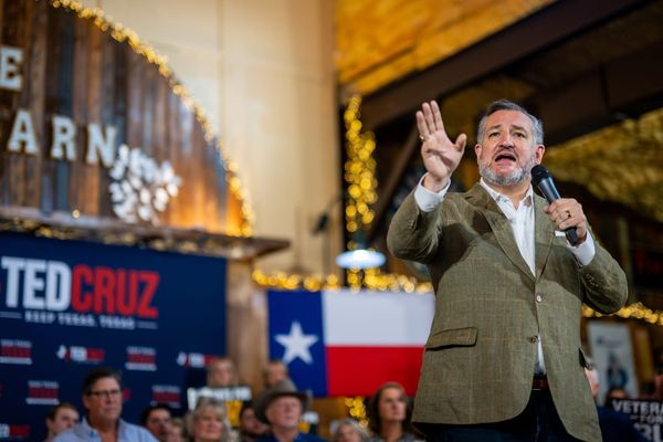 Sen. Ted Cruz in a tweet suit speaking at an event in front of a Texas flag