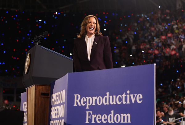 kamala harris smiling in front of a reproductive freedom sign at a podium