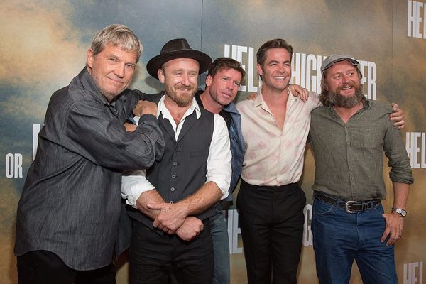 five men standing on a red carpet for a movie premiere, with a sign for Hell or High Water behind them