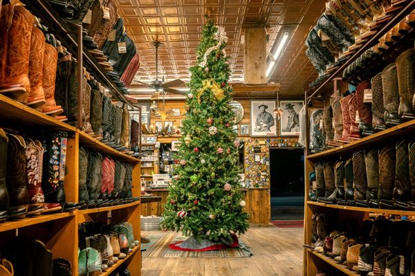 two shelves full of cowboy boots on either side of the frame, with a christmas tree in the middle