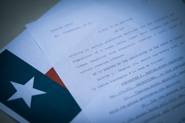 A court document, Texas’ abortion law, resting on top of a Texas flag on a desk