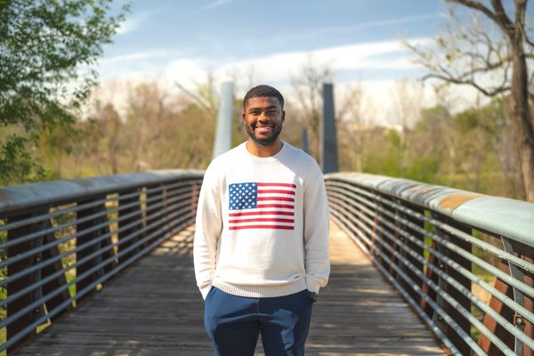 Isaiah Martin standing on a bridge wearing a sweater with the American flag