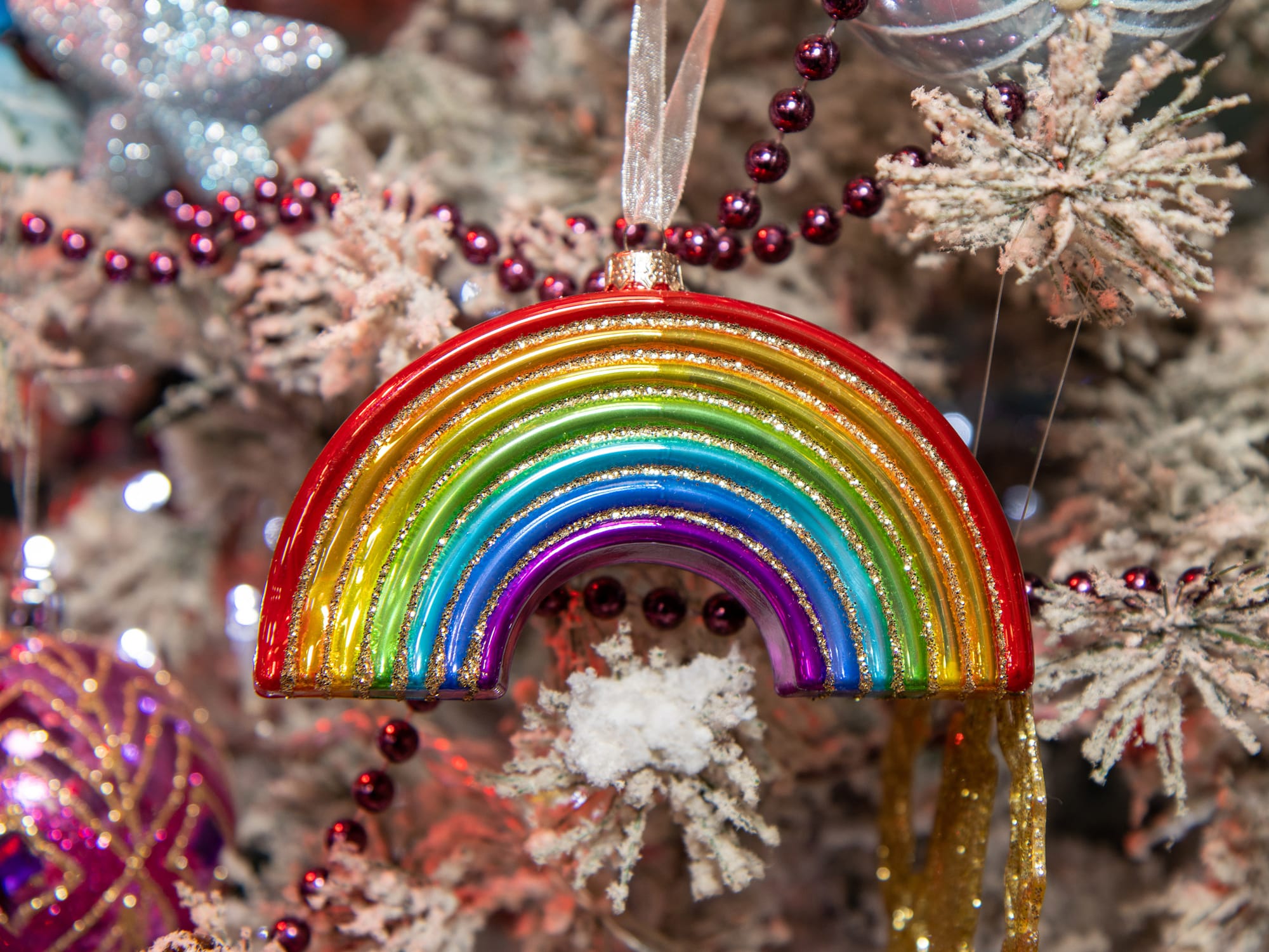 A Christmas ornament in the Shape of a rainbow on a festive Christmas tree