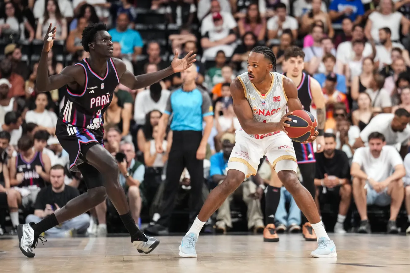 Un joueur de l'AS Monaco en maillot blanc, ballon en main, défendu par un joueur du Paris Basketball lors d'une rencontre entre les deux clubs