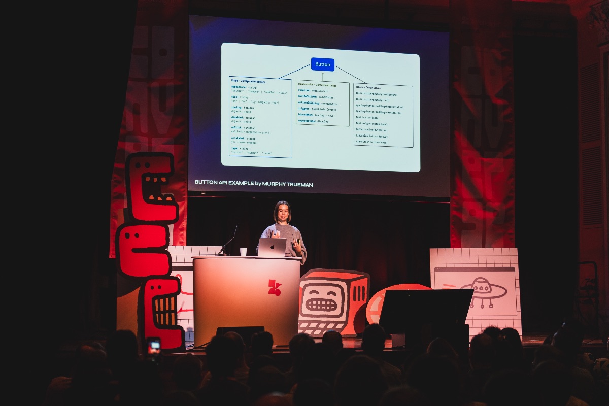 Elyse Holladay presenting at Converge conference with a button API diagram on screen