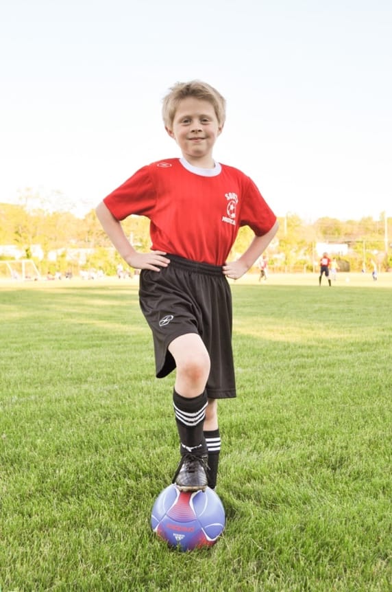 A child standing on a football ball

AI-generated content may be incorrect.