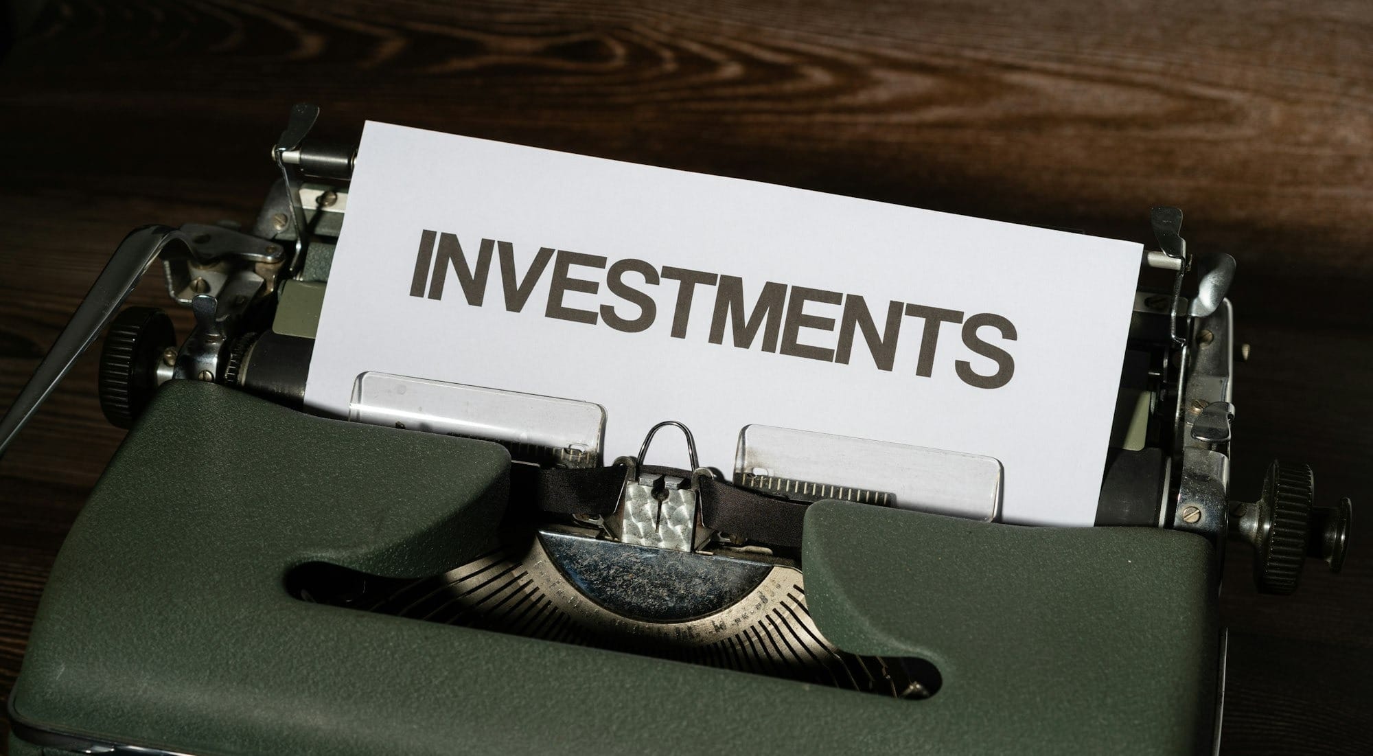 a close up of a typewriter with a paper that reads investments