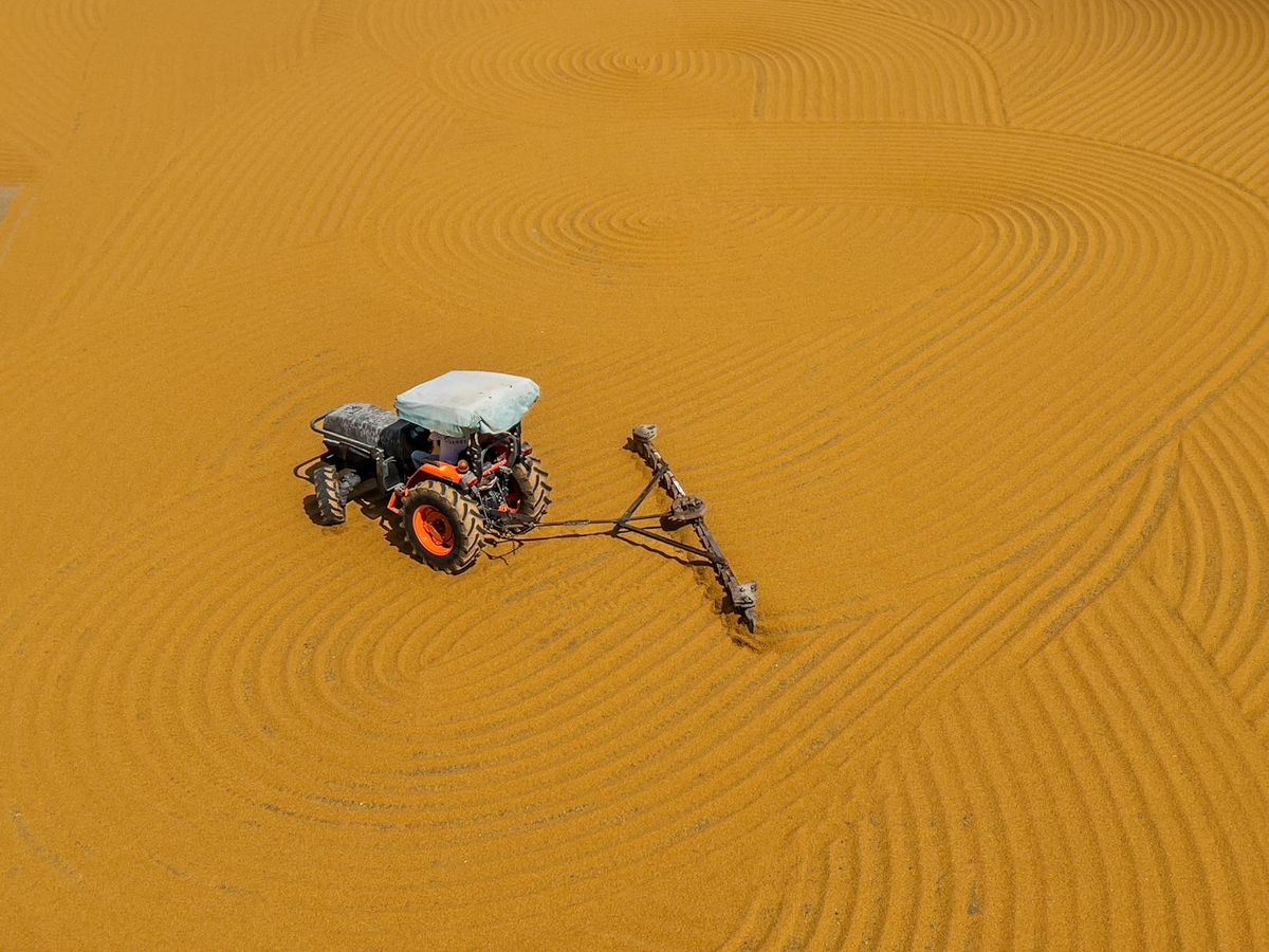 a tractor with plough ploughing brown sand