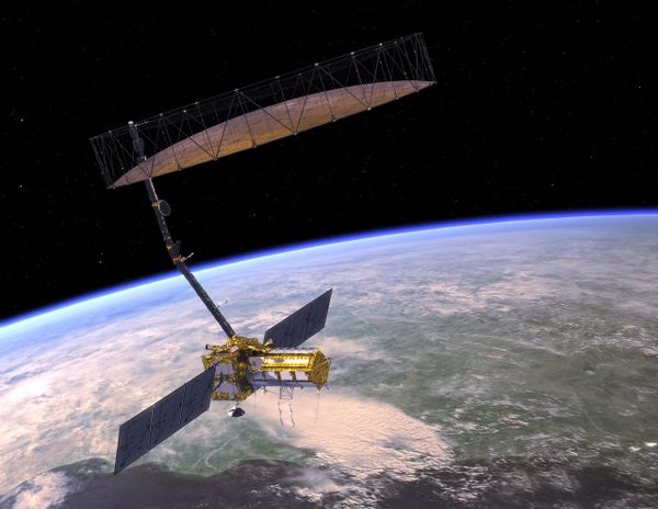 An artist's concept of NISAR orbiting Earth. The satellite's mesh antenna and reflector are visible overhead, at the end of t