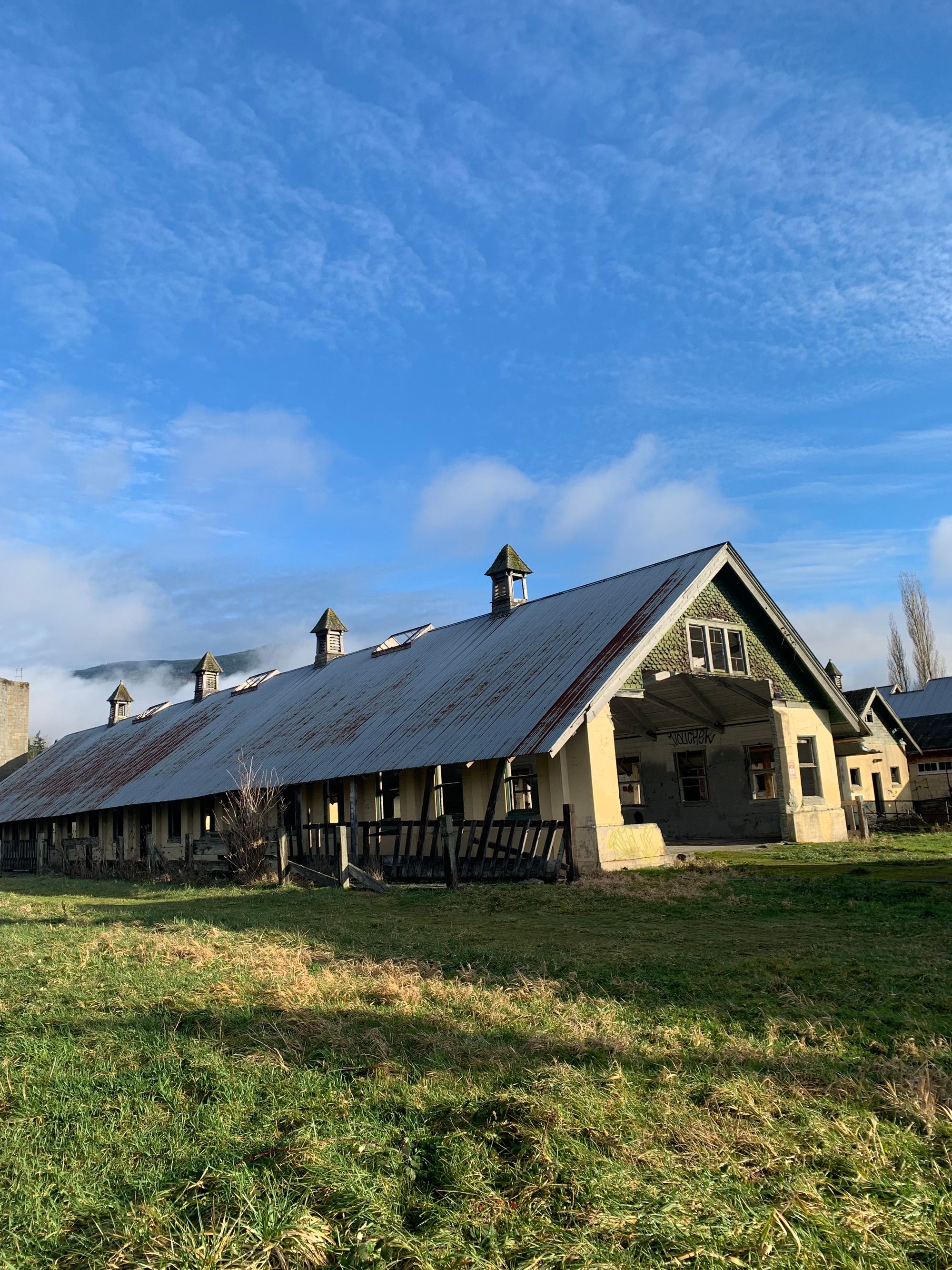 yellow dairy barn, blue sky with clouds