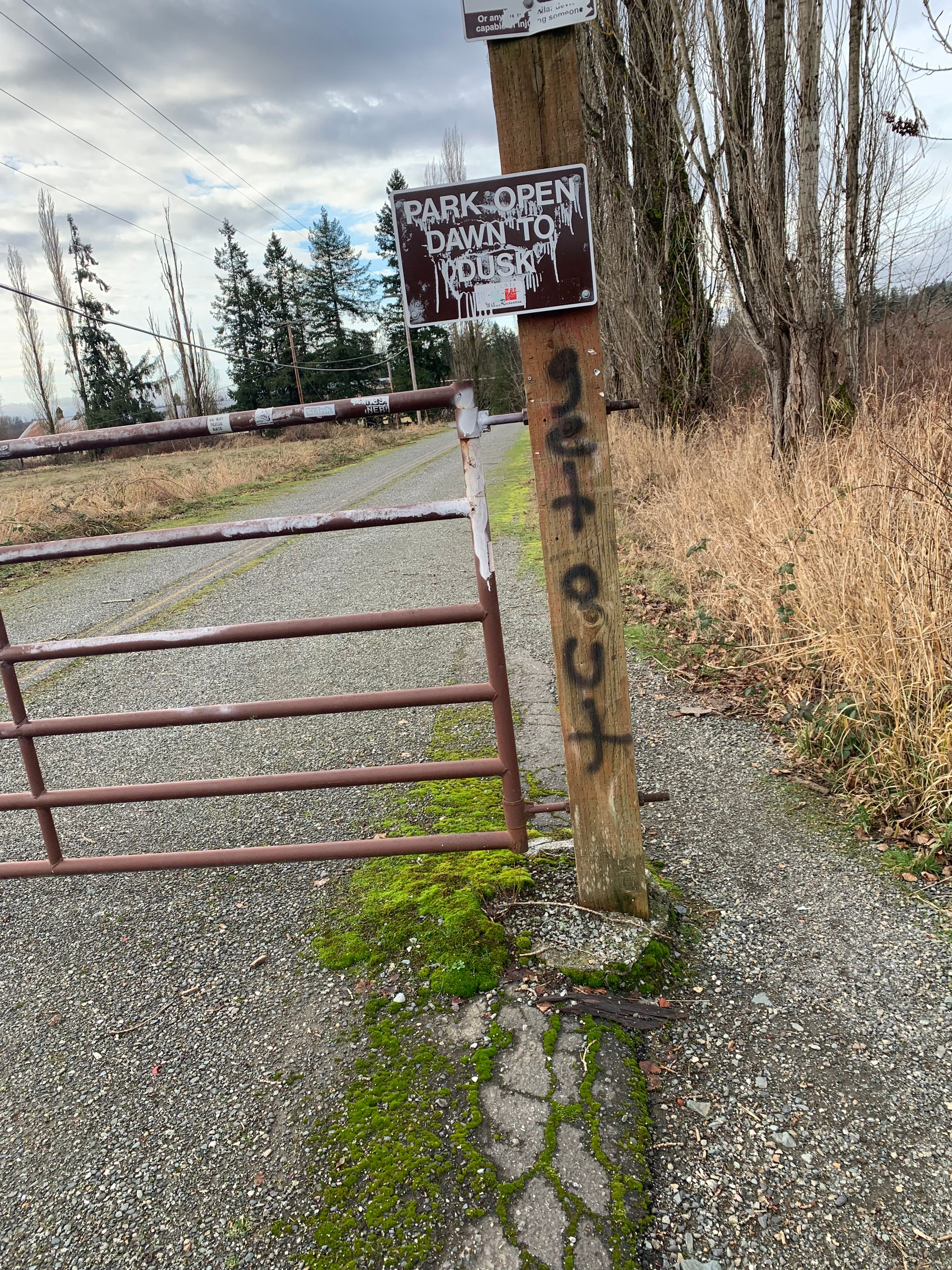 battered gate & fence post with graffiti reading 'get out'