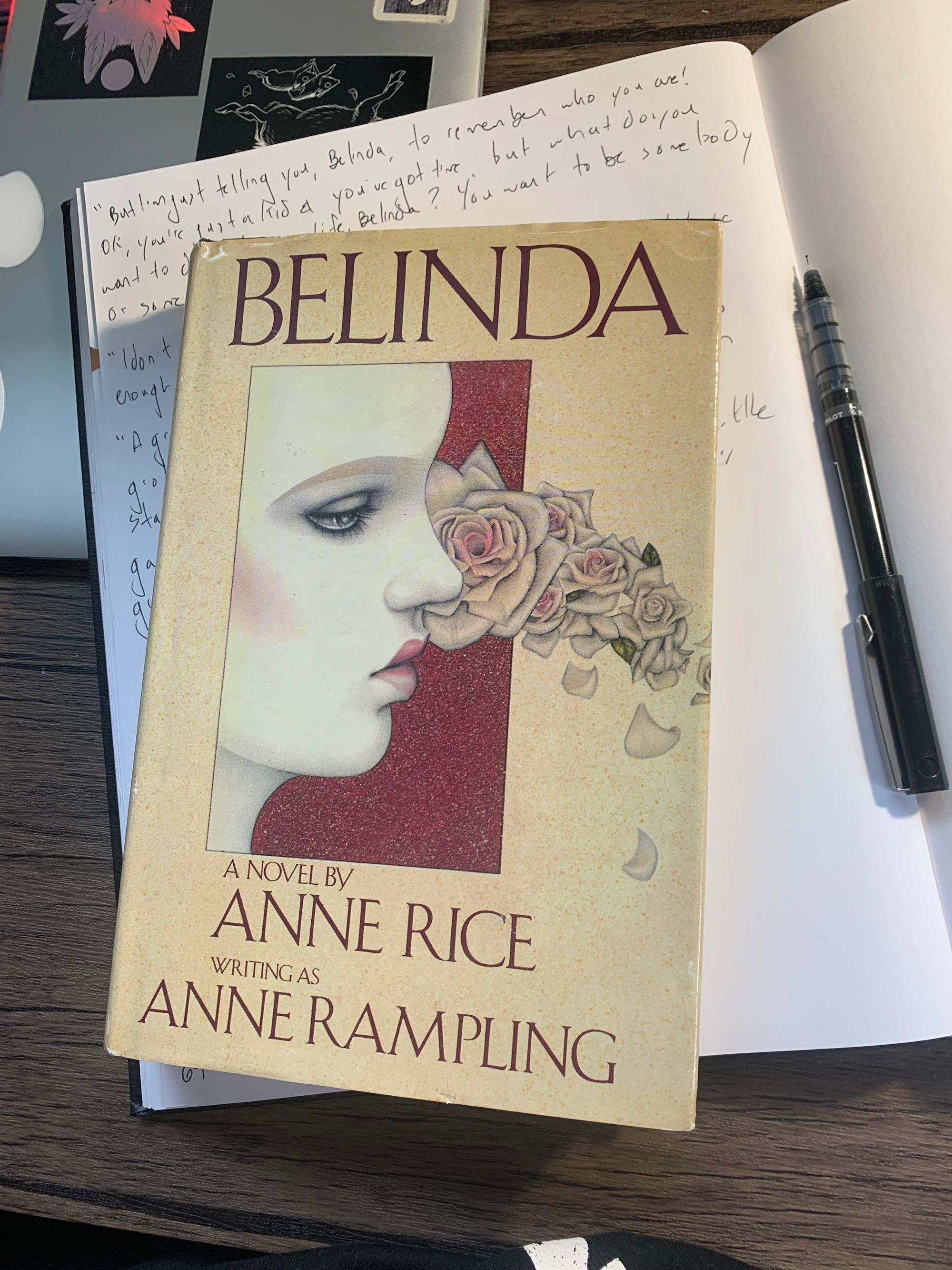 hardcover copy of Belinda by Anne Rice resting on white online notebook, black pen