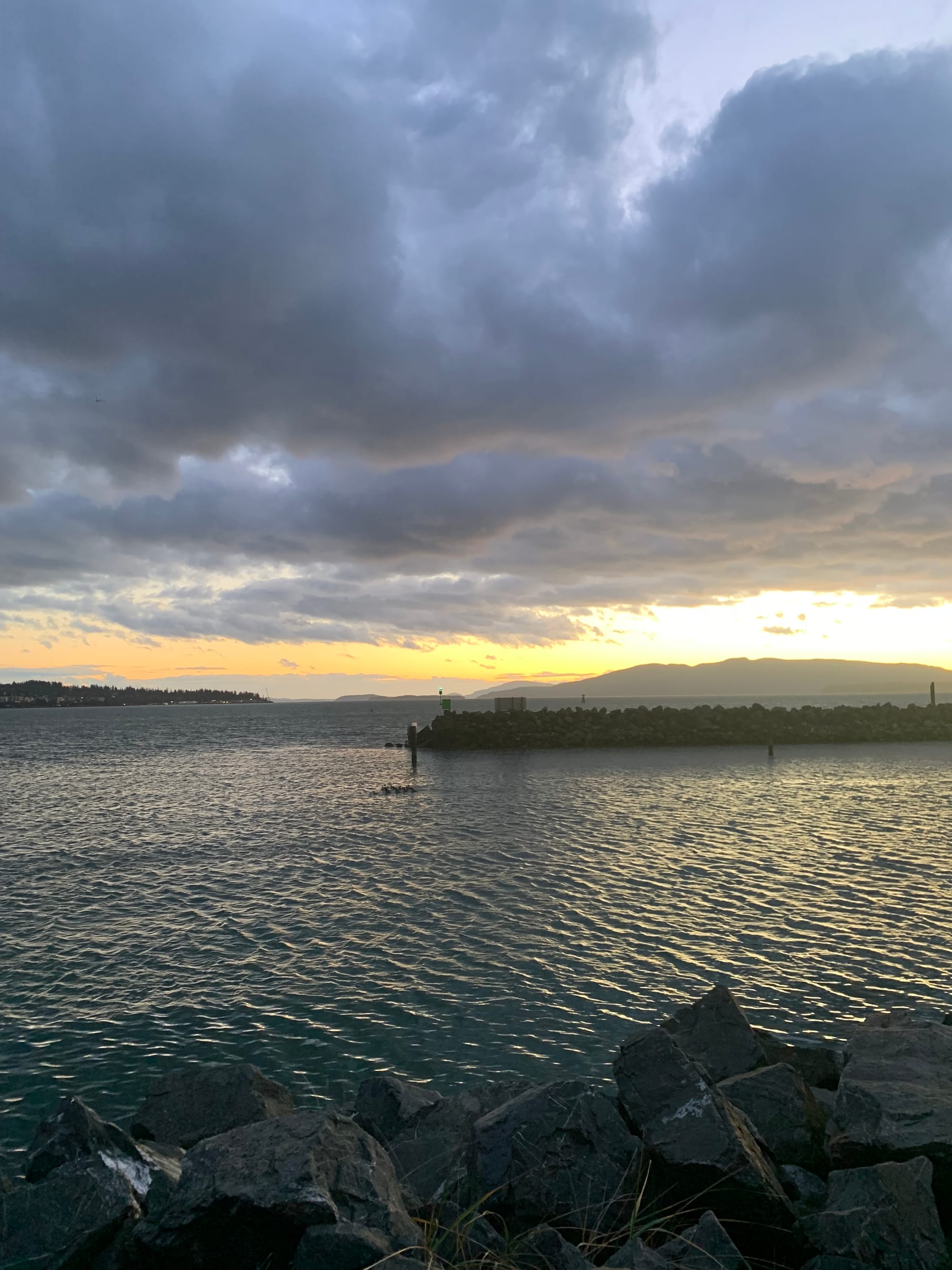 sunset over a long jetty & grey water