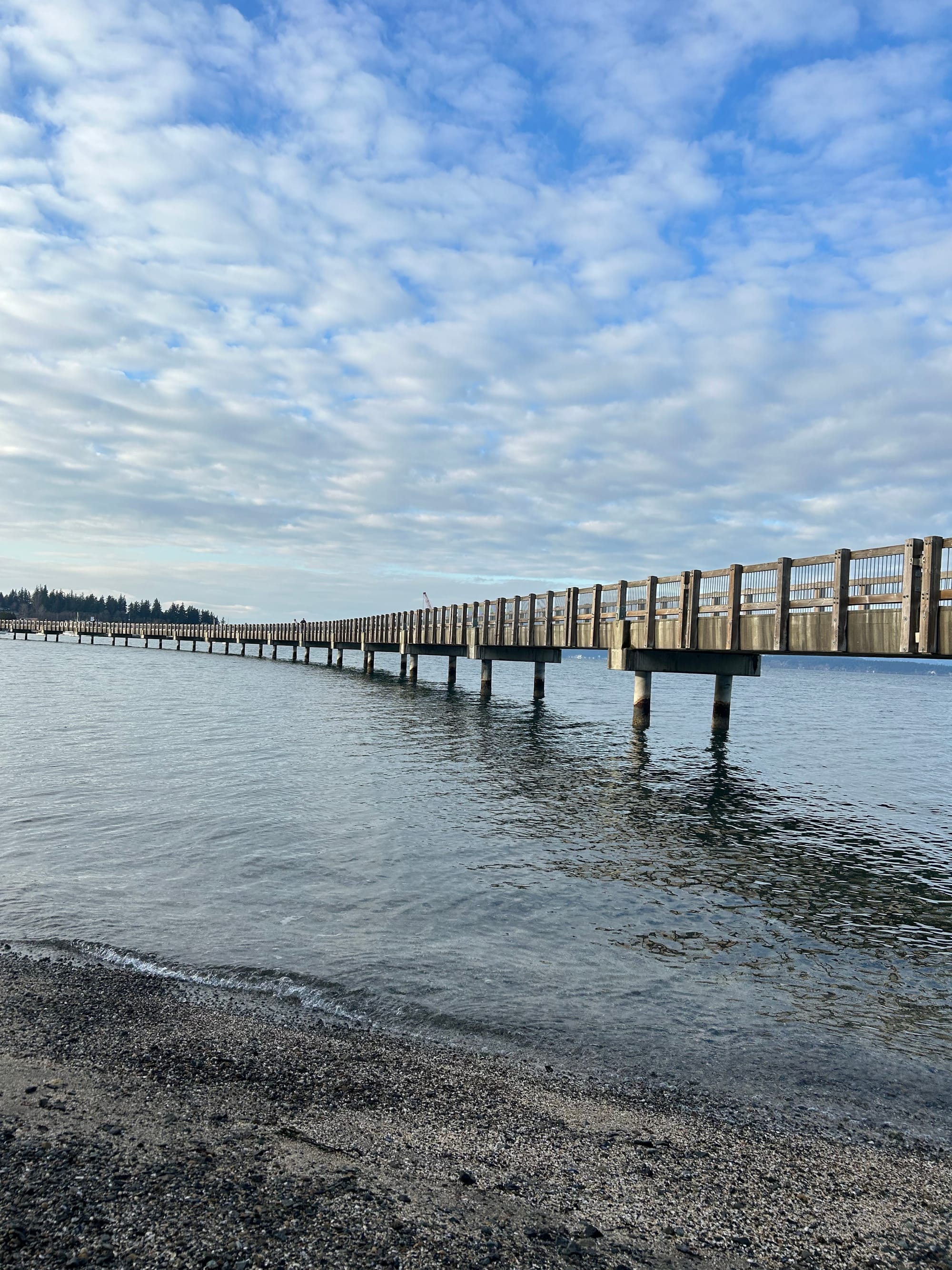 long boardwalk, sandy beach, blue sky with fluffy white clouds