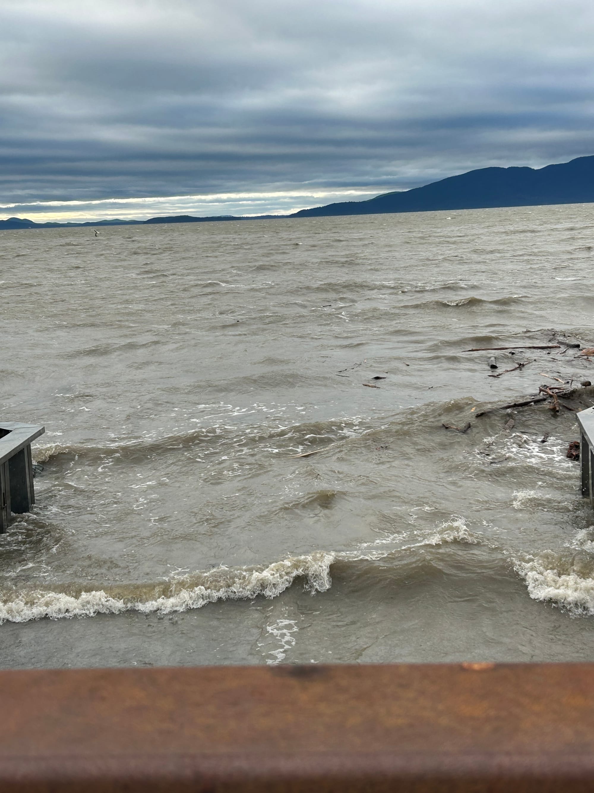 grey brown bay water, grey sky, islands in the distance