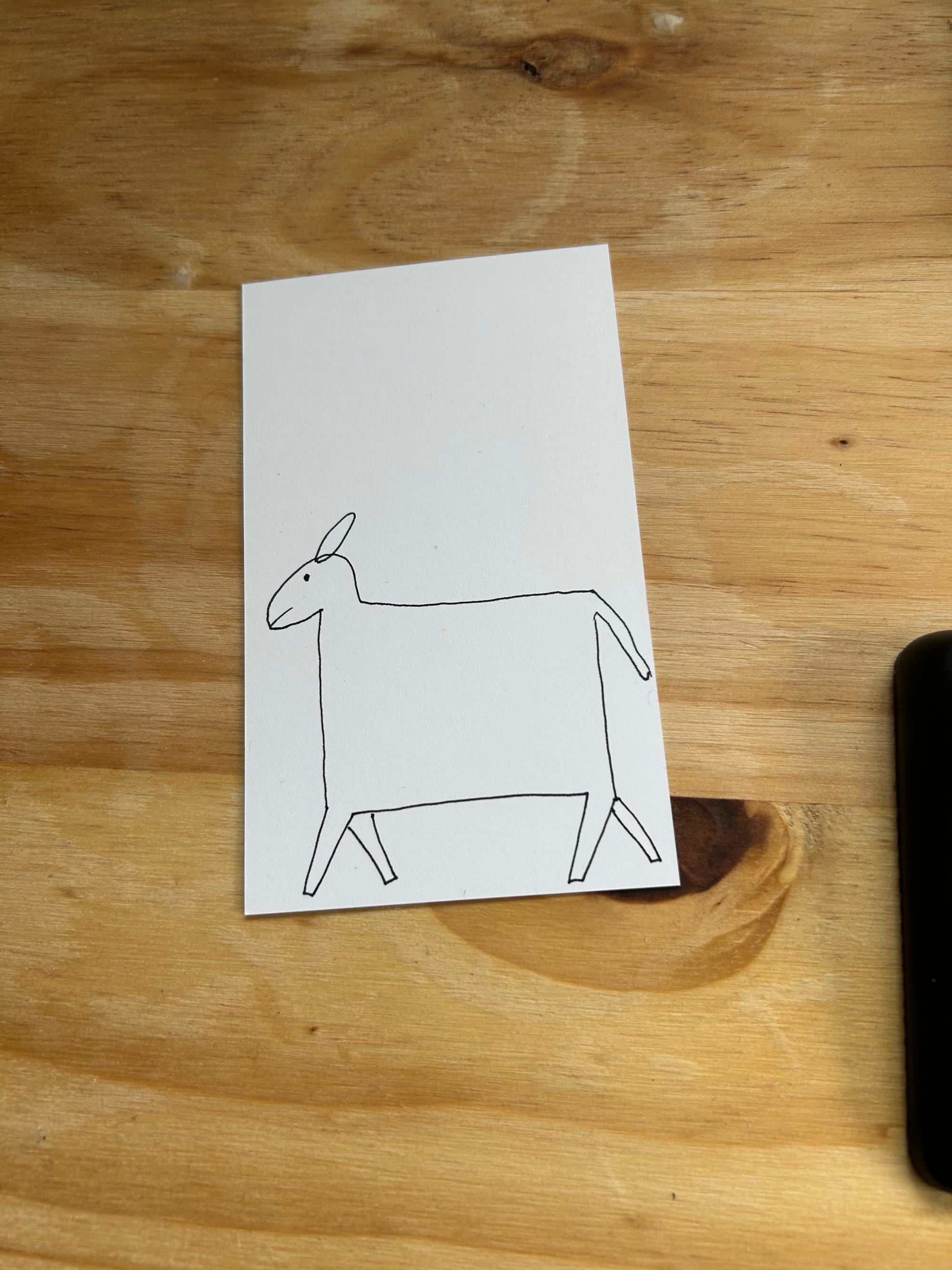 white card with a very square badly drawn horse on it sitting on a wooden table