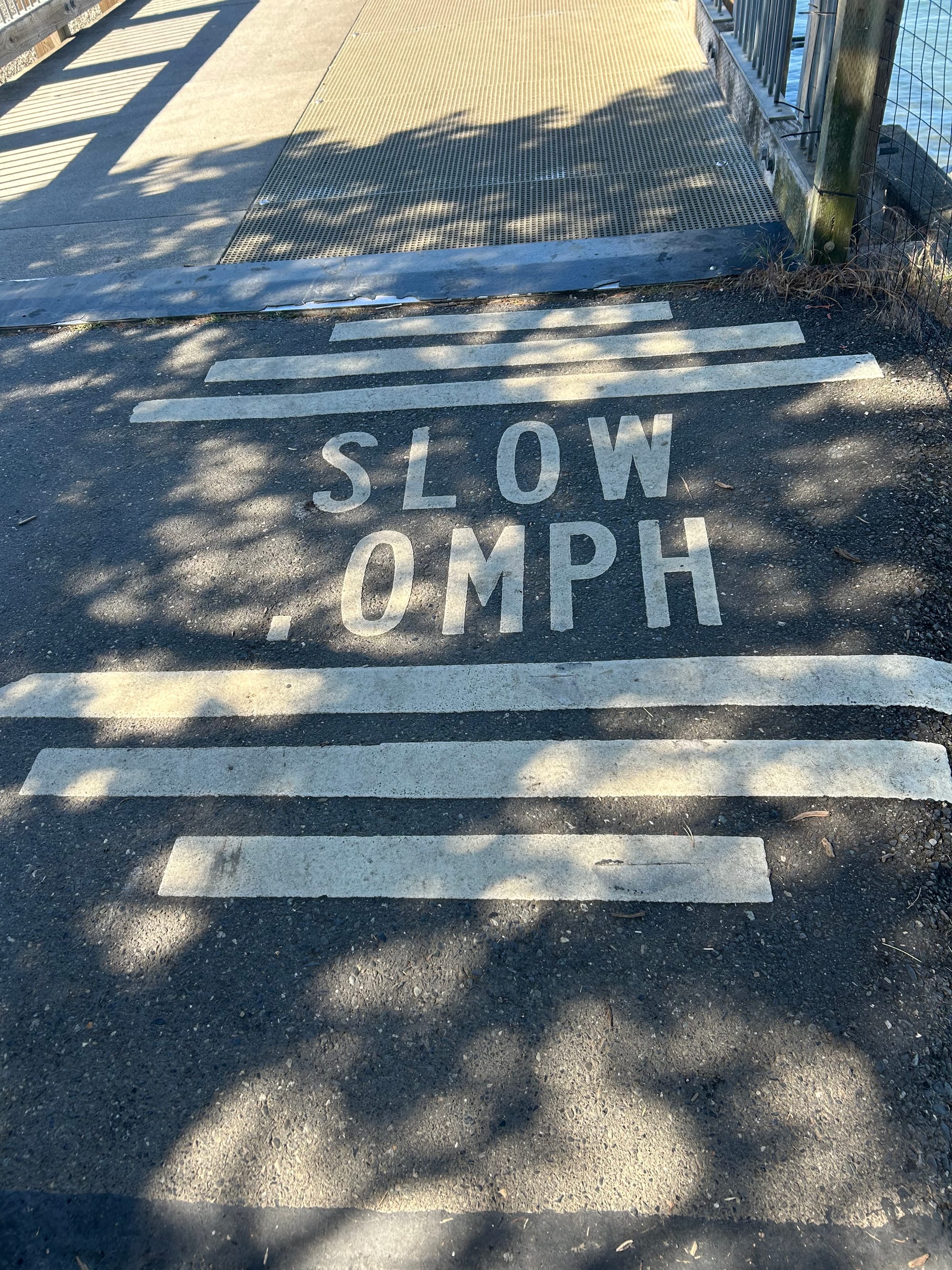 pavement painted with whitelines and words reading "SLOW .0 MPH", probably should say 10 MPH but the 1 has been removed