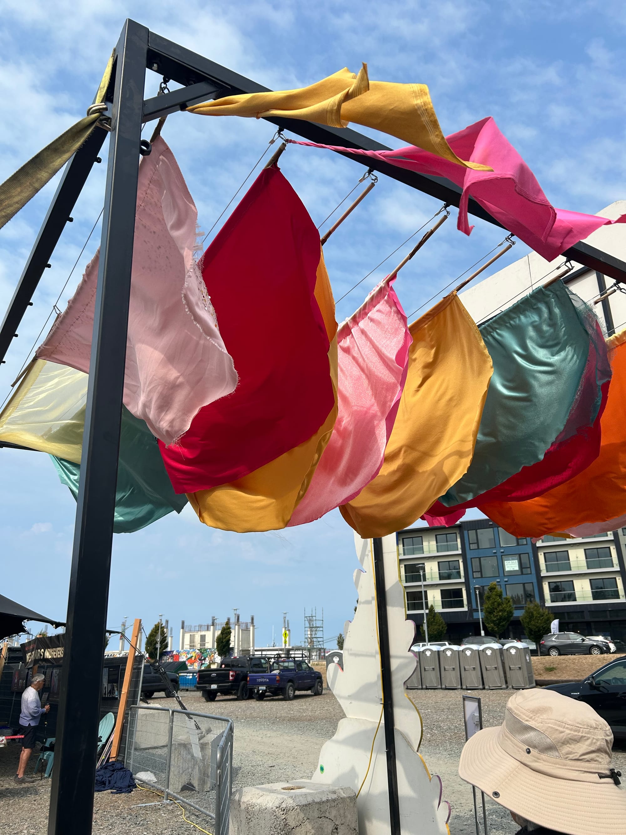 a row of brightly colored fabric on a metal frame, above the entrance to a festival