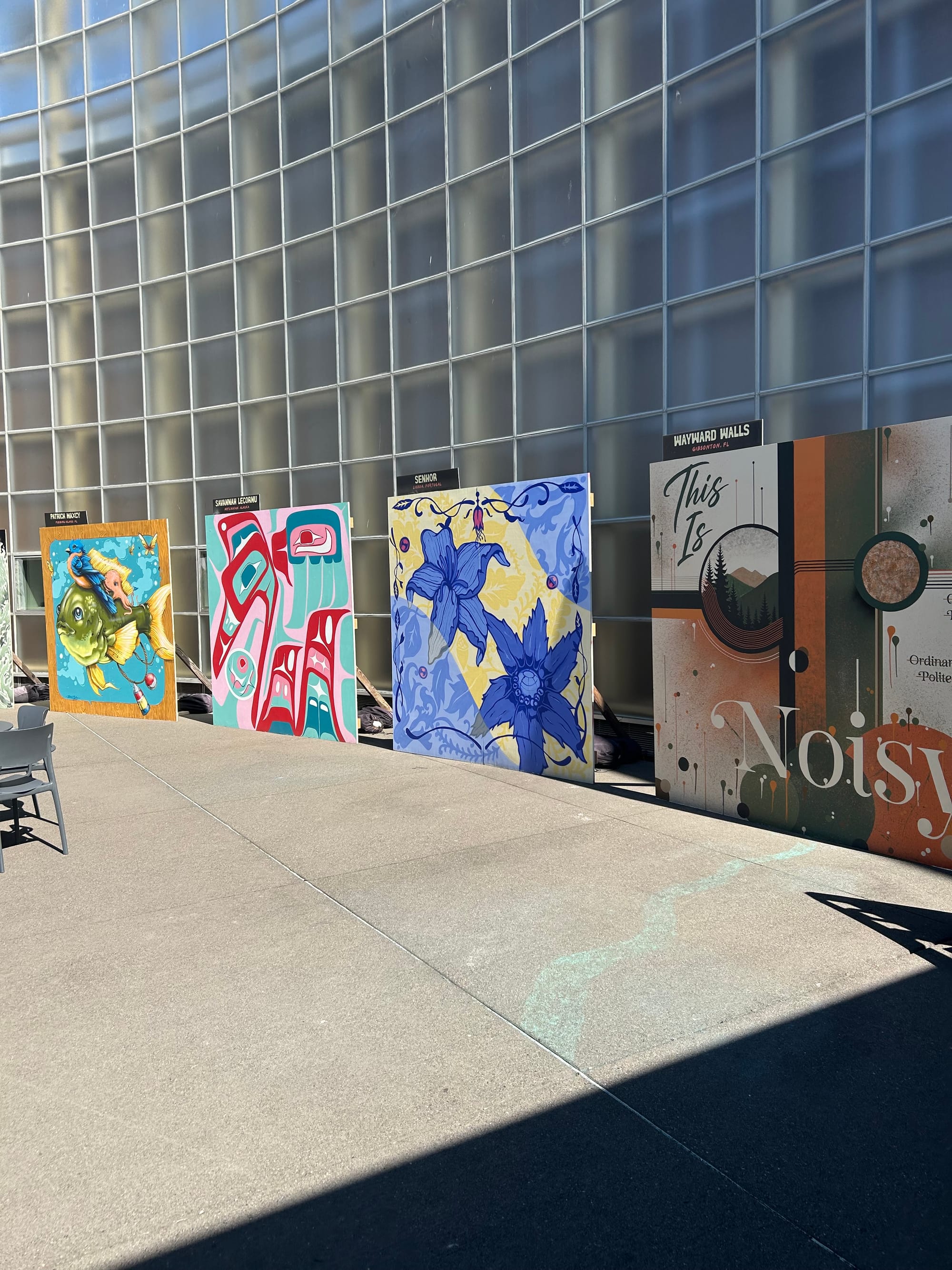 curved wall of transparent square panels with large format square murals set against it.