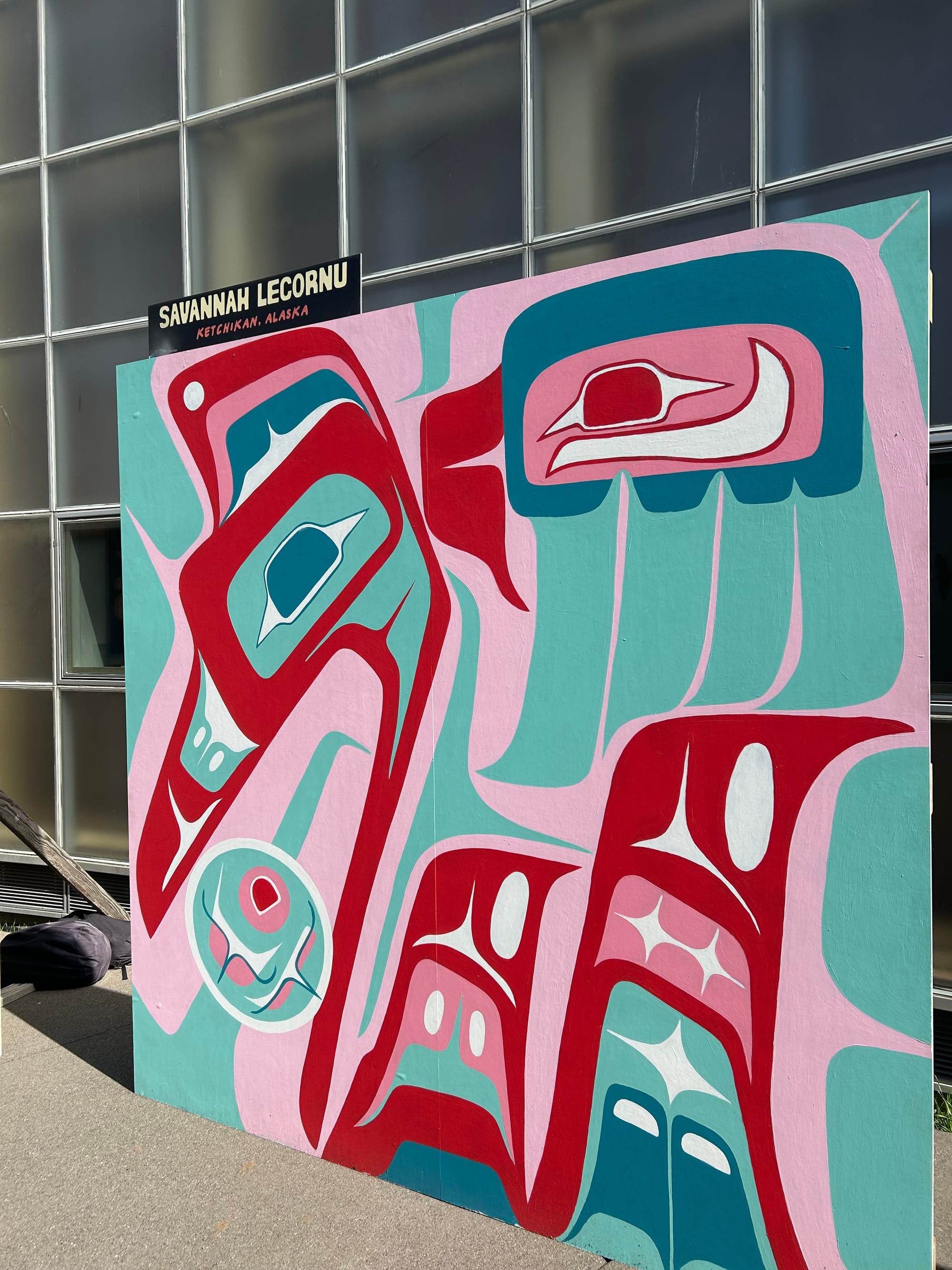 square mural by Savannah Lecornu, pink and red and aqua, of stylized bird heads & other shapes