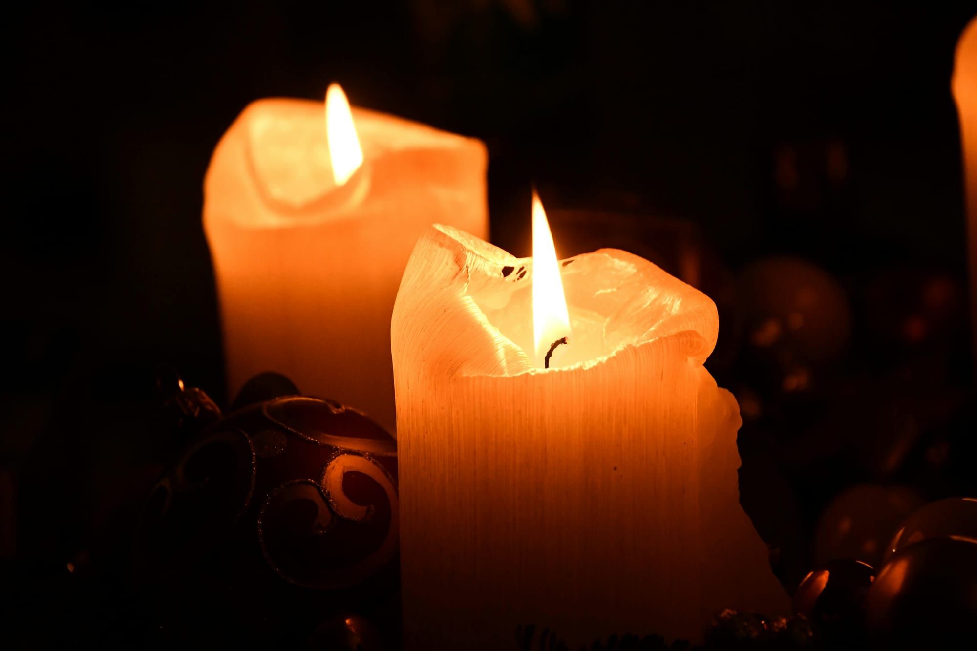 deux bougies orangées brûlent dans la nuit