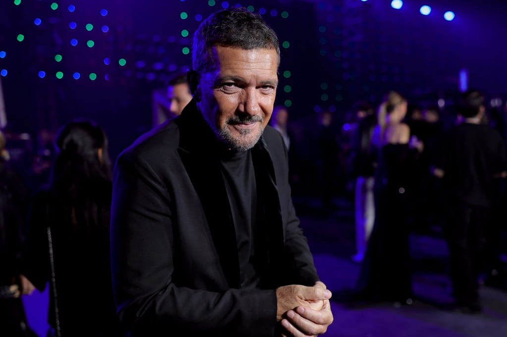 Actor Antonio Banderas poses for a photo indoors, wearing a black suit and turtleneck.