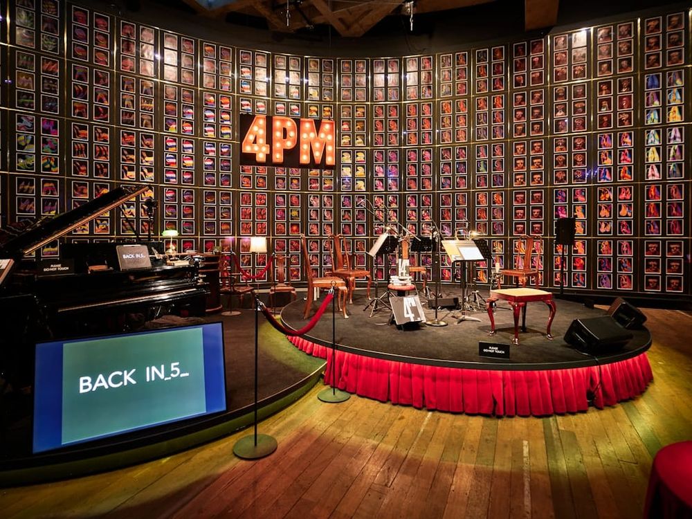 Stage with piano and framed photos on wall.