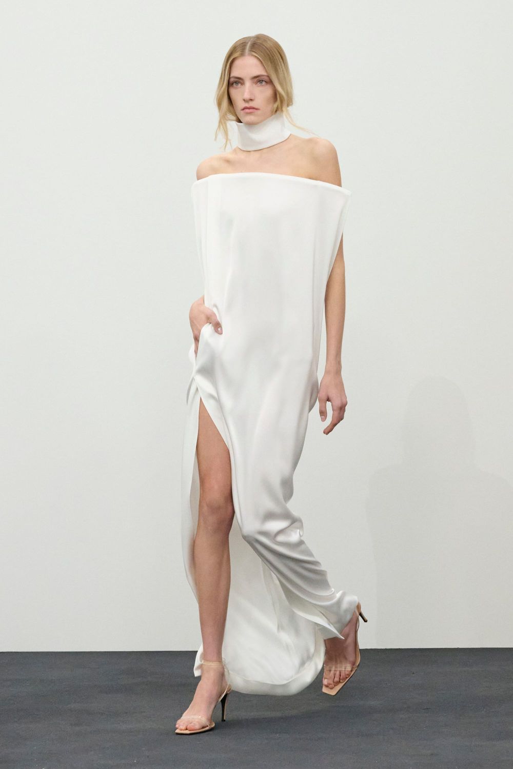 A runway shot from the Courrèges Fall 2026 collection showing one of the signature white architectural pieces—ideally a mini dress or structured coat with geometric cutouts, paired with th...