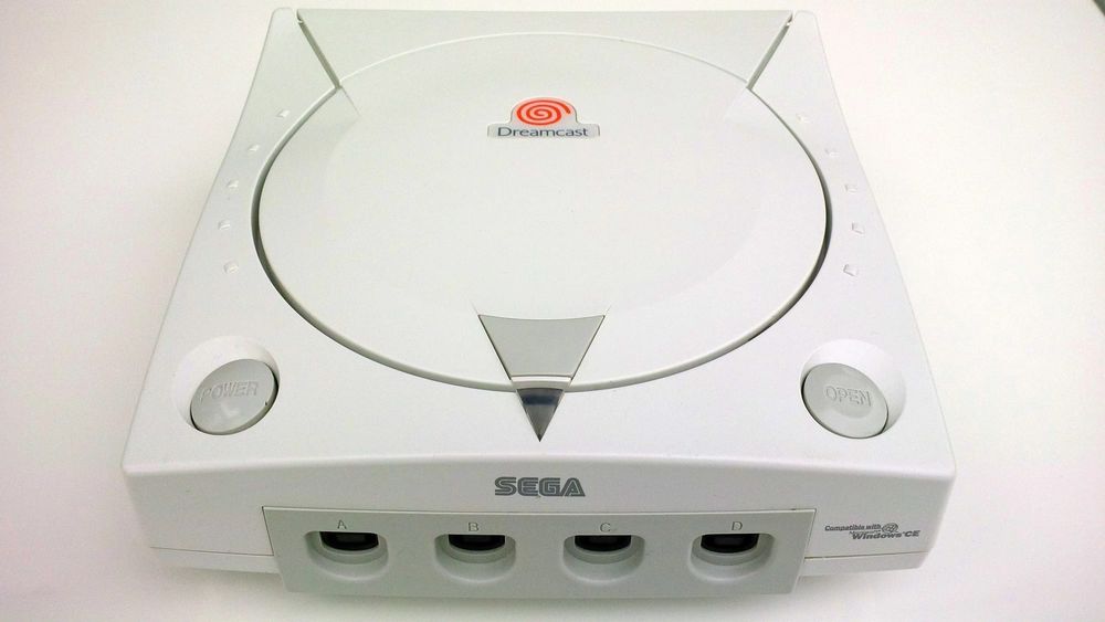 A Dreamcast console, still functional, with a modern indie game case next to it — emphasizing the contrast between 'dead' hardware and active development. Alternatively, a shot of the Pixe...