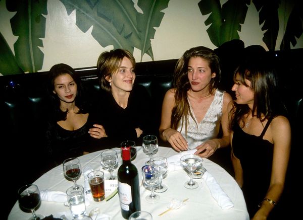 A candid, grainy photograph from an actual 1990s party or event—people talking, no phones visible, the kind of moment that wouldn't be photographed today because everyone would be on their...